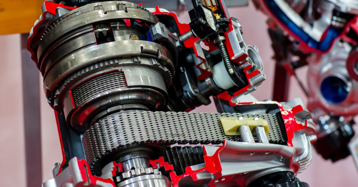 A cutaway transfer case showing metal gears, a chain, red-edged casing, shafts, and exposed mechanical parts.