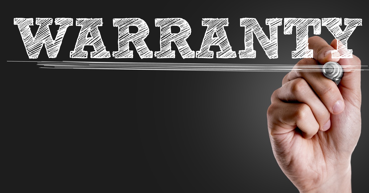 A hand with a pen writes out the word "Warranty" in big, white letters in front of a dark background.
