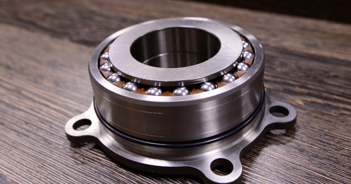 A transfer case input bearing sits on a wooden surface. It features ridges on the side and shines in the light.