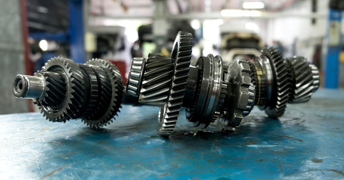 Several parts of a continuously variable transmission sit on a blue surface inside a mechanic's shop.